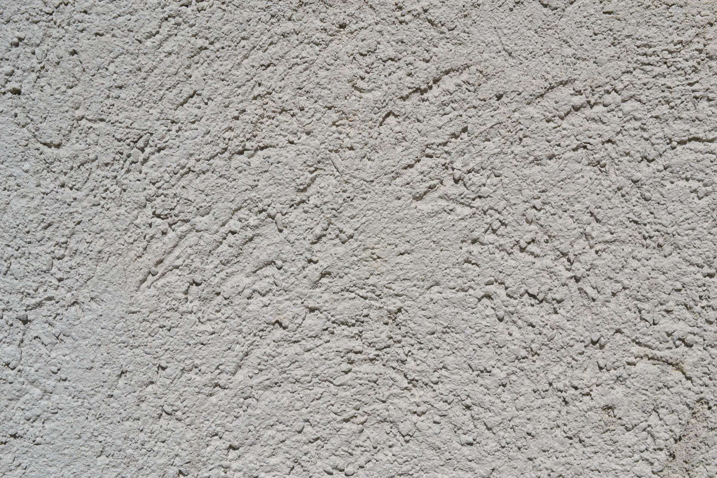 Gros plan sur un crépi de façade ribé gris