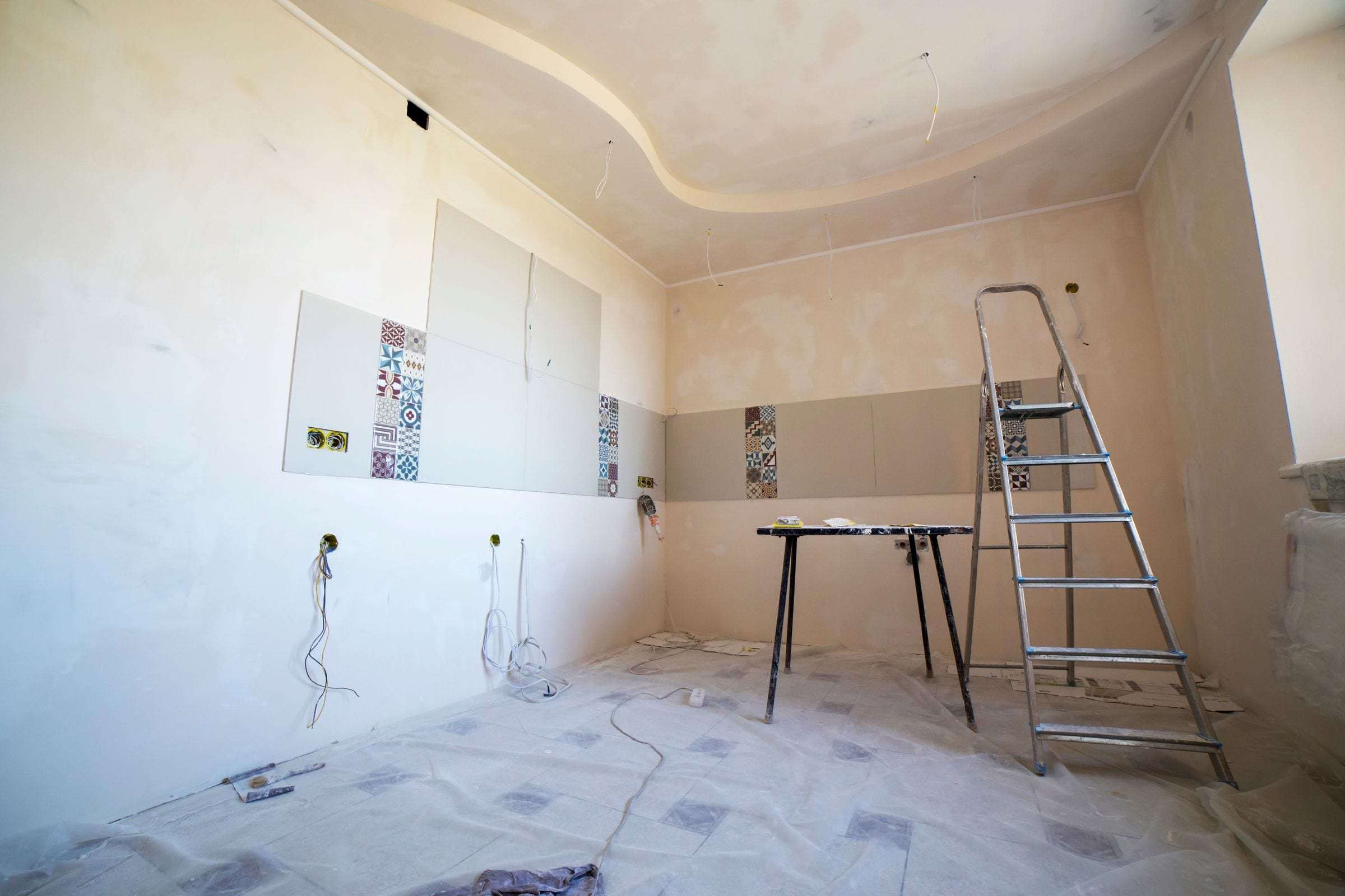 Pièce en travaux au sol protégé, escabeau et murs en cours de remise en état
